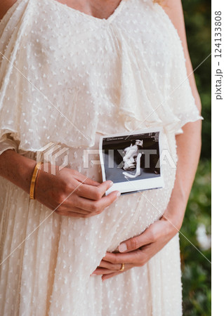 Expectant Mother Holding Ultrasound of Baby Bump 124133808
