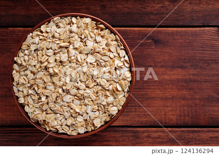 Uncooked Rolled Oats in Brown Pottery Bowl for Vegan Diet and Whole Grain Nutrition, Copy Space, Top View 124136294