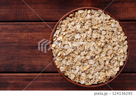 Uncooked Rolled Oats in Brown Pottery Bowl for Vegan Diet and Whole Grain Nutrition, Copy Space, Top View 124136295