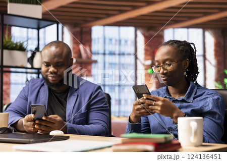 African american couple checking their online correspondence on phones, sending emails before starting daily freelancing tasks. Young adults living and working remotely together. 124136451
