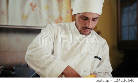 Italian Man Chef In Uniform Peels Potatoes On Wooden Cutting Board At His Home 124136640
