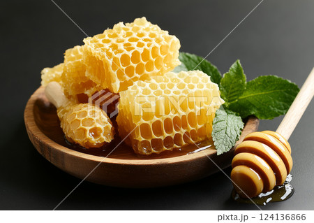 Various Types of Honeycomb on Wooden Platter with Fresh Mint Leaves and Honey Drizzle 124136866