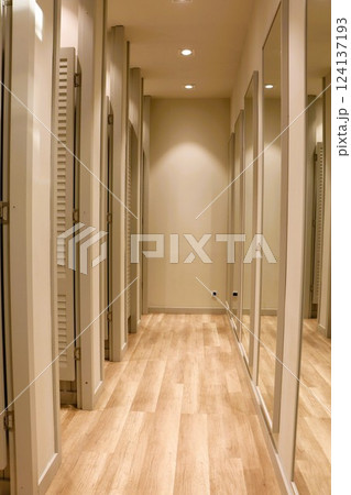 A Stylish Retail Fitting Room Featuring Mirrors and an Elegant Wooden Floor Design 124137193