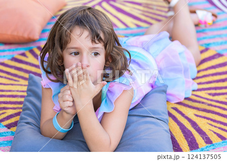 Adorable toddler girl is on the bright mat outdoors in the garden. 124137505