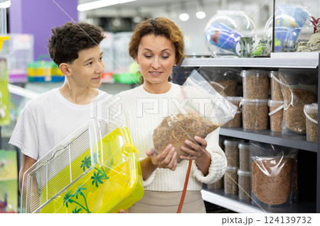 Family mom and son in animal goods store examines packaging of dry food for turtles Family mom and son in animal goods store examines packaging of dry food for turtles 124139732