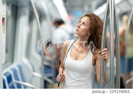 Adult woman stands in subway car Adult woman stands in subway car 124139862