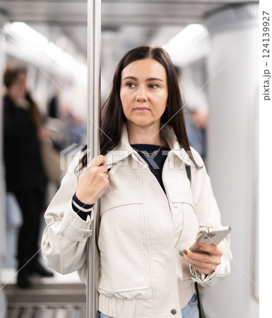Woman with phone stand in metro carriage. 124139927