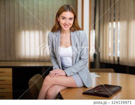 Woman in suit sitting on table 124139971