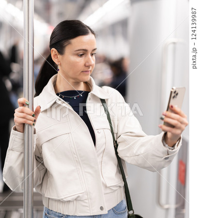 Woman in metro carriage points phone camera at an information board 124139987