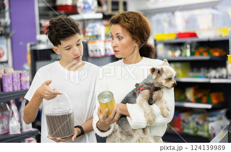 Teenager with mother and Yorkshire terrier choosing dog food in store 124139989