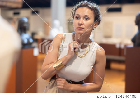 Woman curiously observing antique artifacts in historical museum Woman curiously observing antique artifacts in historical museum 124140489