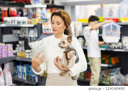 Female owner of Yorkshire terrier choosing dry dog food in pet store Female owner of Yorkshire terrier choosing dry dog food in pet store 124140495