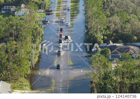 Hurricahe fainfall flooded Florida road with evacuating cars and surrounded with water houses in suburban residential area 124140736