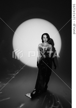 Glamorous Woman in a Metallic Dress Posing Under Dramatic Spotlight 124141291