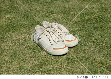 Sneakers on green grass, tennis sport concept. Sneakers on green grass, tennis sport concept. 124141854