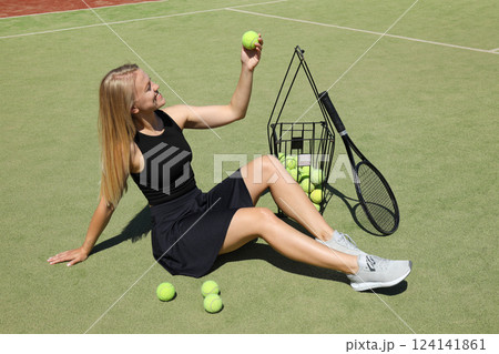 A blonde girl plays tennis on the sports court. 124141861