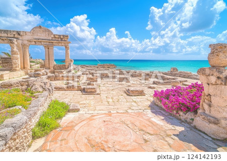 Historic ruins by the beach with vibrant flowers under a bright sky 124142193