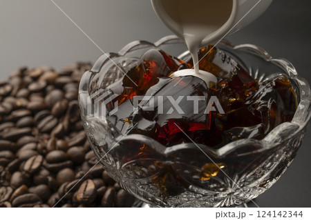 ガラスの器に盛り付けた冷たいコーヒーゼリーにミルクをかける コーヒー豆 ガラスの器に盛り付けた冷たいコーヒーゼリーにミルクをかける コーヒー豆 124142344