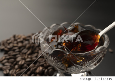 ガラスの器に盛り付けた冷たいコーヒーゼリーをスプーンで持ち上げる コーヒー豆  124142349