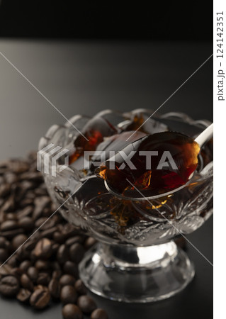ガラスの器に盛り付けた冷たいコーヒーゼリーをスプーンで持ち上げる コーヒー豆  124142351