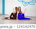Two women practicing partner yoga in a studio 124142970