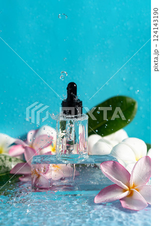 A serum dropper splashes in water, amidst delicate plumeria flowers, embodying hydration. 124143190