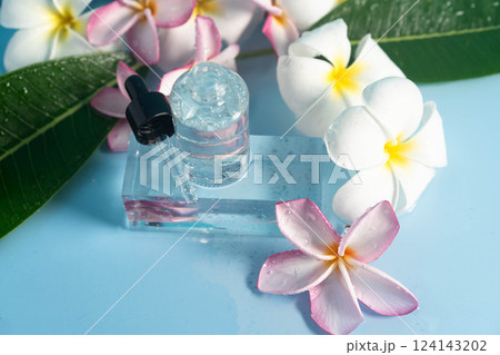 A pretty blue setting features a serum bottle beside lovely plumeria flowers for hydration. 124143202