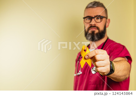Healthcare professional showing support with yellow ribbon indoors Healthcare professional showing support with yellow ribbon indoors 124143864