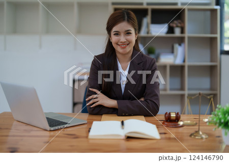 female attorney advisor at a law firm reviews legal documents at her desk equipped with a laptop notebook and scales of justice in the office female attorney advisor at a law firm reviews legal documents at her desk equipped with a laptop notebook and scales of justice in the office 124146790