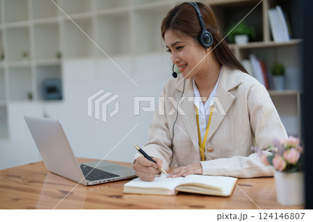 Asian businesswoman wears a headset while participation in an online video conference discussing marketing and finance strategies effectively 124146807