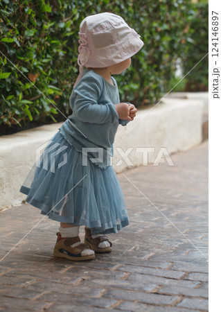 Playful little baby girl toddler in blue dress, outdoor portrait Playful little baby girl toddler in blue dress, outdoor portrait 124146897
