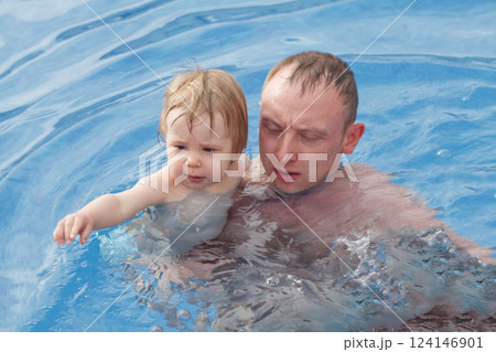 Young father swimming with cute baby girl in swimming pool Young father swimming with cute baby girl in swimming pool 124146901
