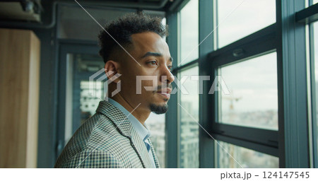 Businessman gazing at the urban skyline from an office. 124147545
