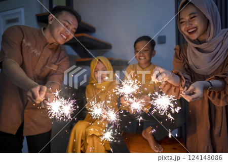 An Indonesian Muslim family playing fireworks in their hometown. Concept of Happy Lebaran, Eid Al Fitr, Idul Fitri, and Ramadan Mubarak celebration An Indonesian Muslim family playing fireworks in their hometown. Concept of Happy Lebaran, Eid Al Fitr, Idul Fitri, and Ramadan Mubarak celebration 124148086