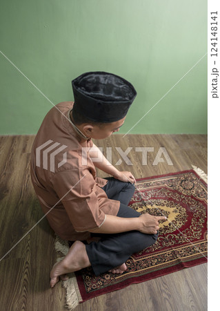 Portrait of an Indonesian muslim man praying (salat) at home. Concept of Islamic praying or Ramadan Kareem 124148141