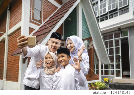 Portrait of the Indonesian Muslim family with a mobile phone taking a selfie or video call while celebrating Eid Mubarak. Concept of Happy Lebaran, Eid Al Fitr, Idul Fitri, and Ramadan Mubarak Portrait of the Indonesian Muslim family with a mobile phone taking a selfie or video call while celebrating Eid Mubarak. Concept of Happy Lebaran, Eid Al Fitr, Idul Fitri, and Ramadan Mubarak 124148143