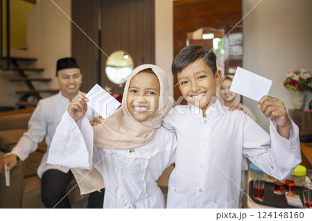 Portrait of Indonesian Muslim child showing envelope of money (Thr) from the parent while celebrating Eid Mubarak. Concept of Happy Lebaran, Eid Al Fitr, Idul Fitri, and Ramadan Mubarak celebration Portrait of Indonesian Muslim child showing envelope of money (Thr) from the parent while celebrating Eid Mubarak. Concept of Happy Lebaran, Eid Al Fitr, Idul Fitri, and Ramadan Mubarak celebration 124148160
