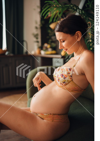 Young pregnant woman relaxing on a couch in a cozy indoor setting Young pregnant woman relaxing on a couch in a cozy indoor setting 124149110