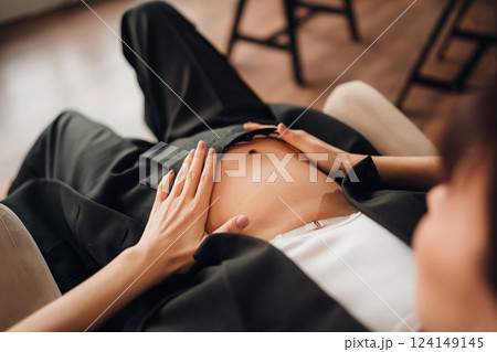 Young pregnant woman gently touching her belly while relaxing at home 124149145