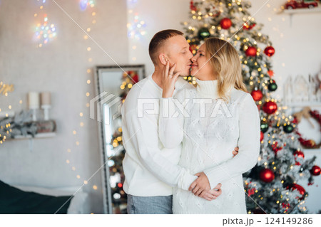 happy man and woman in a room with a Christmas tree.  124149286