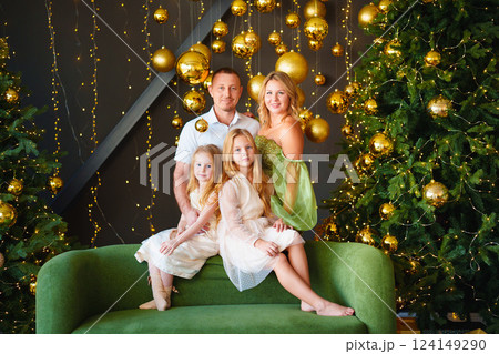 A happy family in elegant clothes on a green sofa at the Christmas tree.  124149290