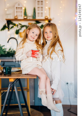 Two cute sisters in the New Year's decor of the kitchen. Two cute sisters in the New Year's decor of the kitchen. 124149347
