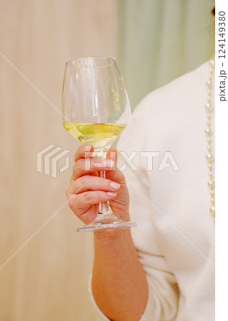 A glass of white wine in a woman's hand.  124149380