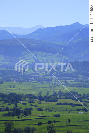 Breathtaking green valley surrounded by misty blue mountains in rural landscape 124149688