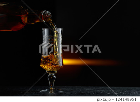 Hard liquor being poured into a glass. Hard liquor being poured into a glass. 124149951