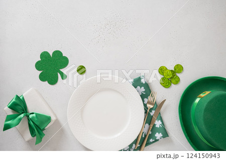 St Patrick's Day banner with white plate, cutlery, table setting, gift, leprechaun hat and clover leaves on white background. View from above. Copy space. St Patrick's Day banner with white plate, cutlery, table setting, gift, leprechaun hat and clover leaves on white background. View from above. Copy space. 124150943
