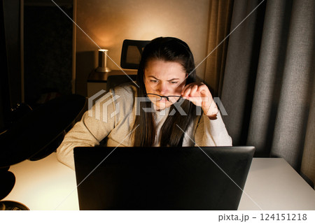 Woman working on computer late evening at home office. Concentrated female freelancer trying to solve business problems. Working and suffering from weariness. 124151218
