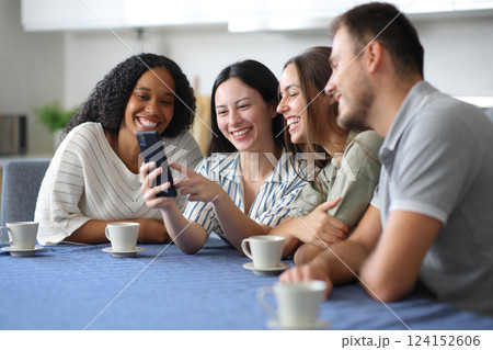 Happy interracial friends using phone in the kitchen 124152606