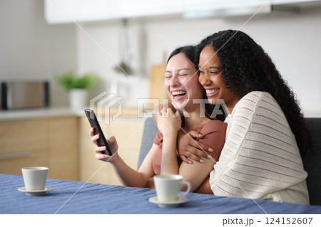 Happy interracial lesbian couple using smart phone 124152607