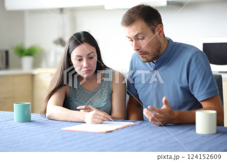 Perplexed interracial roommates checking document at home Perplexed interracial roommates checking document at home 124152609